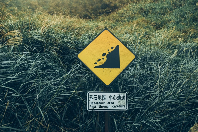台湾台北阳明山，白天绿草旁的黑色和黄色金属标牌