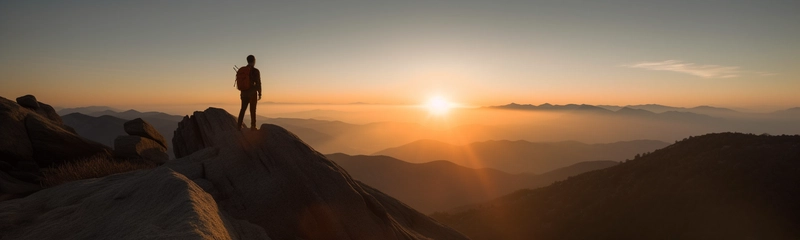 登山者登上山顶，眺望前方广袤无垠的山谷。